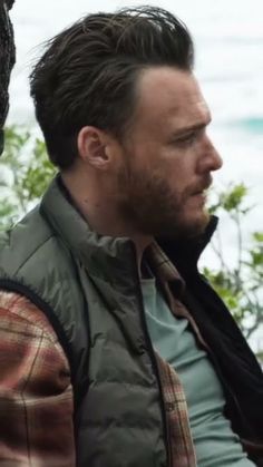 a man sitting next to a tree near the ocean