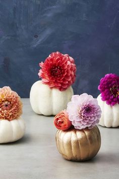 three white pumpkins with flowers in them sitting on a table next to each other