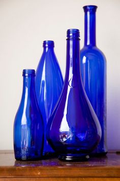 three blue glass bottles sitting on top of a wooden table