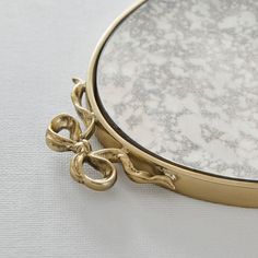 a close up of a mirror on a table with a gold frame and metal handles