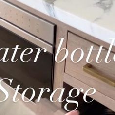 a person is opening the drawer in front of a counter top that says water bottle storage