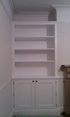 an empty room with white cupboards and shelves