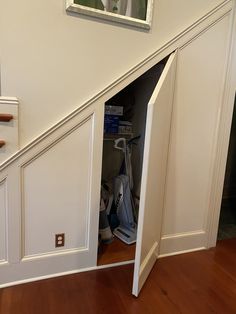 an open door leading to a closet under the stairs in a house with hard wood flooring