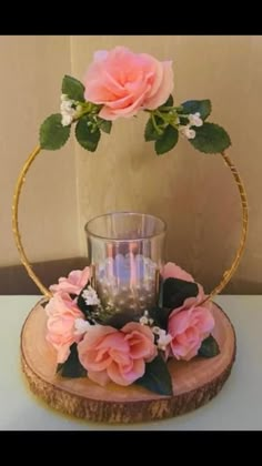 a vase with pink flowers and greenery on top of a wooden slice in front of a wall