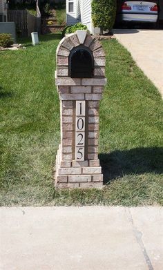 a brick mailbox sitting on the side of a sidewalk in front of a house