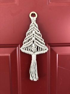 a christmas tree door hanger hanging on a red door with a gold ring around it