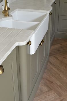 a kitchen with two sinks and gold faucets on the counter top, along with wood flooring