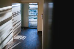 an open door leading into a room with wooden floors and windows on either side of it