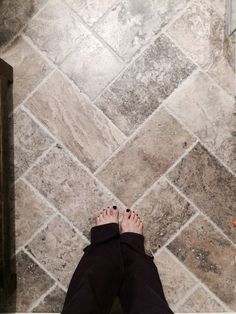 a person standing in front of a tiled floor with their feet up on the ground