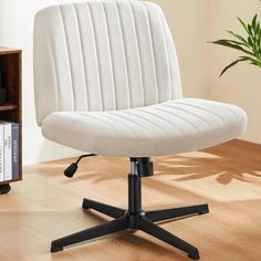 a white office chair sitting on top of a wooden floor next to a book shelf