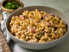 a white bowl filled with macaroni salad next to a wooden spoon on a table