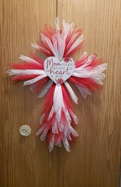 a red and white wreath hanging on a door with a mom's heart written on it