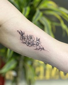 a woman's arm with flowers on it and a plant in the back ground