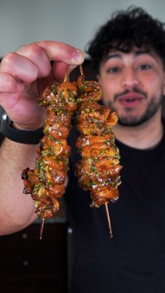 a man is holding up a skewer of food