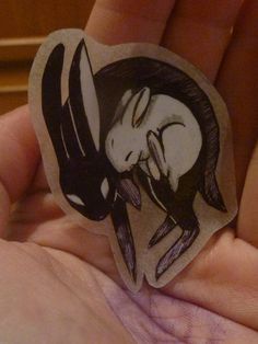 a hand holding a sticker with a drawing of a horse on it's back