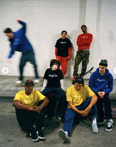 a group of young men sitting next to each other in front of a white wall