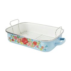 a blue casserole dish with flowers painted on the side and handles, sitting on a white background