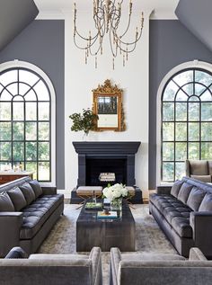 a living room with couches, chairs and a coffee table in front of two large windows