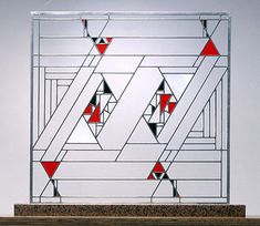 a glass sculpture with red and black geometric shapes on it's sides, against a white background