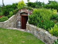 an outdoor garden area with stone walls and green plants on the sides, along with a wooden door