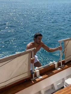 a man on the deck of a boat looking at something in the water behind him