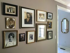 a wall with many framed pictures on it and an open door leading to another room