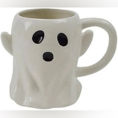 a white coffee mug with black eyes and a ghost's face on the side