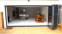 an open sliding glass door leading into a dining room and kitchen area with wooden flooring