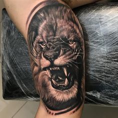 a man's arm with a black and grey tattoo of a lion on it