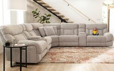 a living room with a sectional couch and coffee table in it, next to a stair case