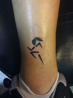 a woman's foot with a tattoo on it that has a running man in the middle