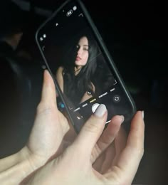 a woman holding up her cell phone to take a selfie with the camera in front of her