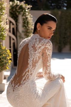 a woman in a wedding dress sitting on the ground with her back to the camera