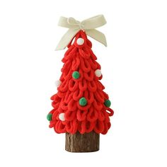 a red knitted christmas tree sitting on top of a wooden pole with a white bow