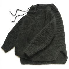 a gray sweater is laying on top of a white surface with a string attached to it