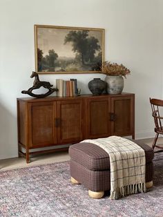 a living room area with a chair, ottoman and painting on the wall above it