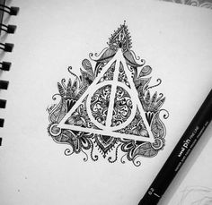 the deathly symbol is drawn on top of a notepad next to a pen