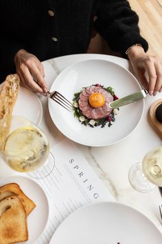 a person sitting at a table with food and wine