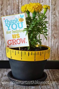 a potted plant with yellow flowers and a sign that says thank you for helping us grow