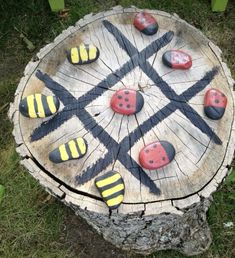 painted rocks arranged on a tree stump in the shape of an arrow and ladybugs