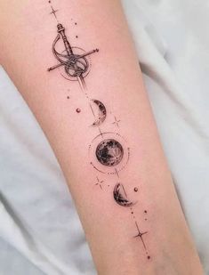 a woman's arm with an arrow and planets tattoo on the left side of her leg