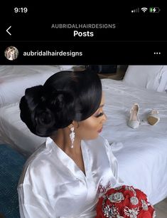 a woman sitting on top of a bed next to a white bedspread and pillows