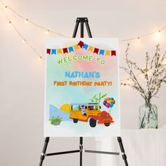 a welcome to nathan's first birthday party sign on an easel with lights in the background