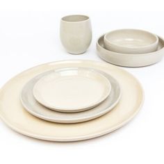 a white table setting with two cups and one plate on the side, next to another set of dishes