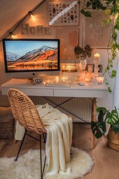 a desk with a computer on it next to a potted plant and some candles