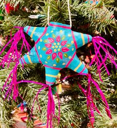 an ornament hanging from a christmas tree decorated with pink and blue decorations,