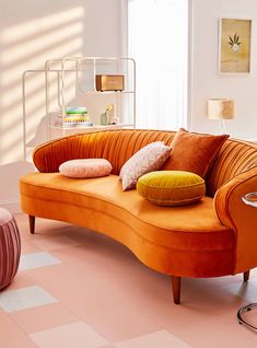 an orange couch sitting on top of a pink floor next to a chair and table