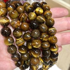 a hand holding several brown tiger eye beads