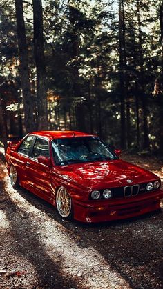 a red car parked in the middle of a forest