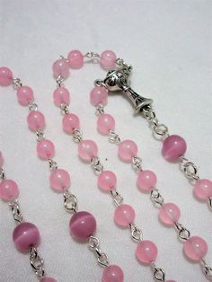 This pink First Communion rosary for girls is made with 6mm pale pink agate rounds and 8mm matte pink cat's eye beads. It measures about 27 inches around the body and has a 5 inch cross drop. The crucifix and the chalice are Italian made oxidized silver. I hand turned the silver plated wires. This rosary will be slipped into a velvet bag and shipped in a bubble mailer. Handmade Pink Rosary With Round Beads, Pink Rosary With 8mm Round Beads, Pink Beaded Rosary With Round Beads, Pink Rosary With Round Beads For First Communion, Pink Rosary For First Communion, Pink Beaded Rosary, Catholic Communion, Catholic Rosary, Matte Pink